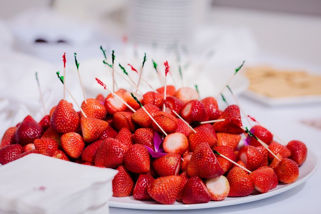 A plate of strawberries on toothpicks on a table.