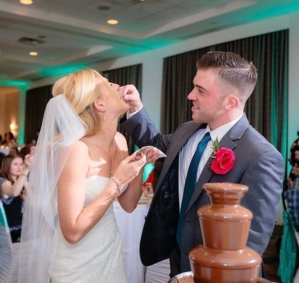A bride and groom are eating chocolate from a chocolate fountain.
