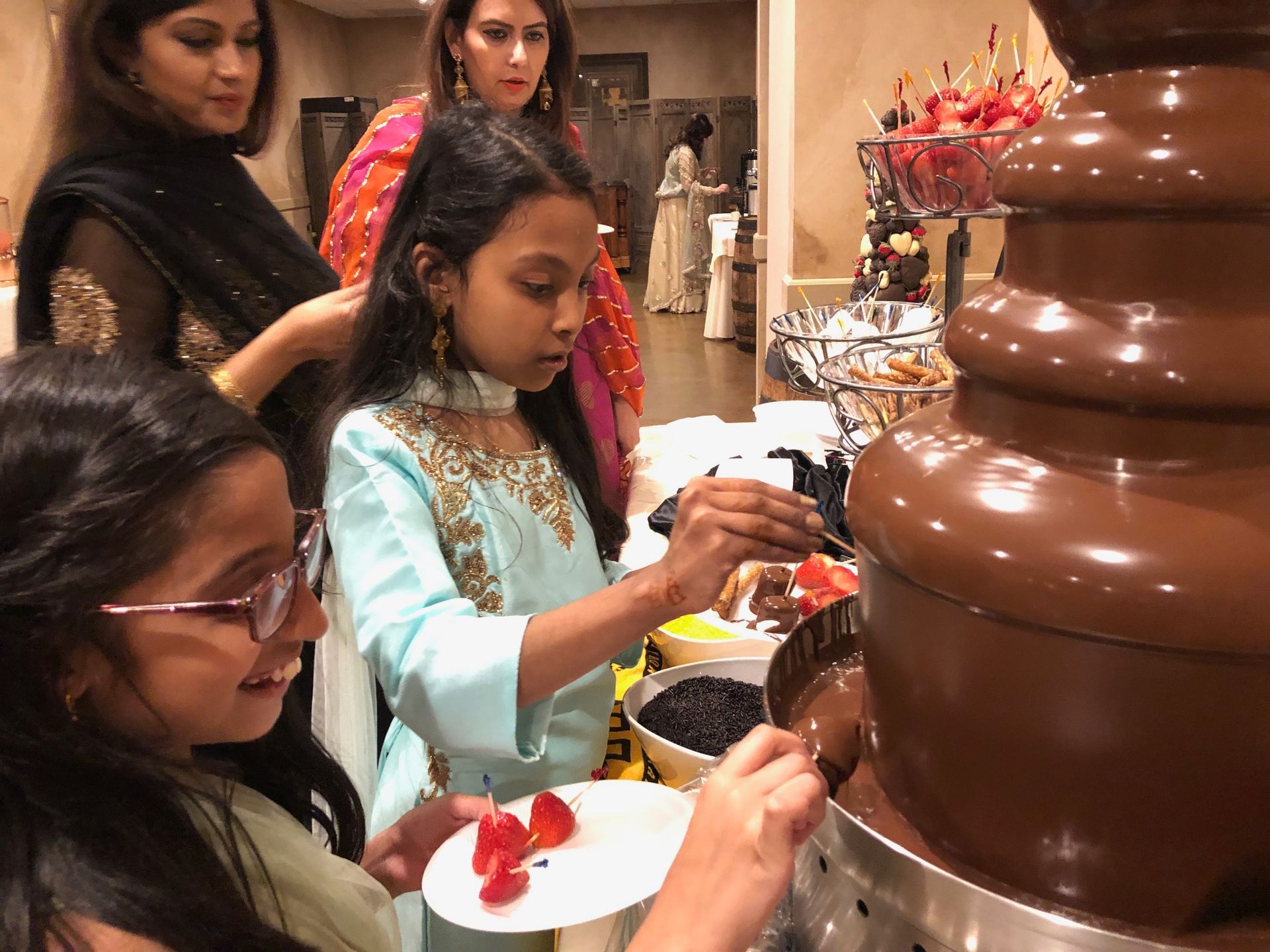A group of people are standing around a chocolate fountain.
