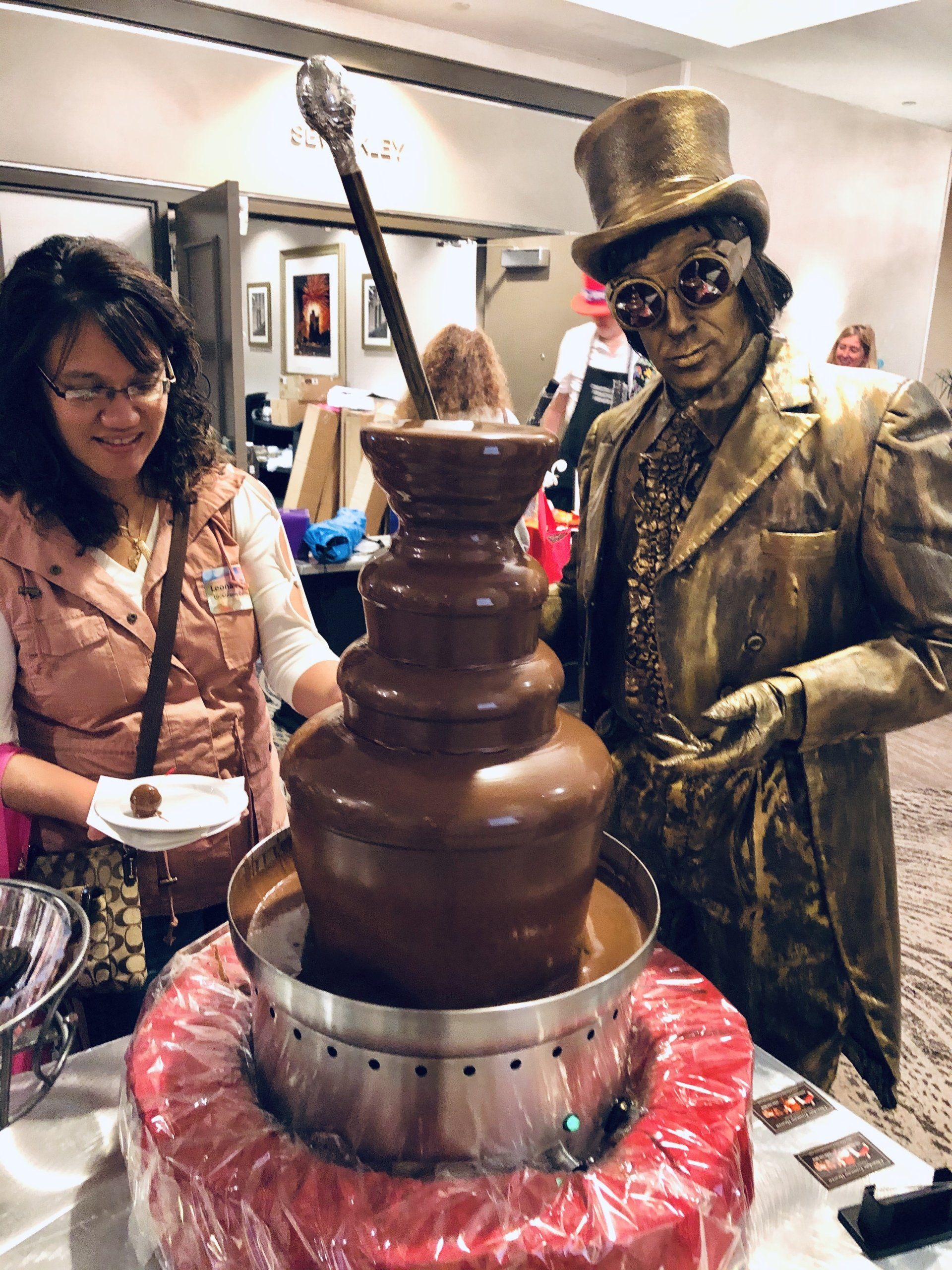 A man in a top hat is standing next to a chocolate fountain.