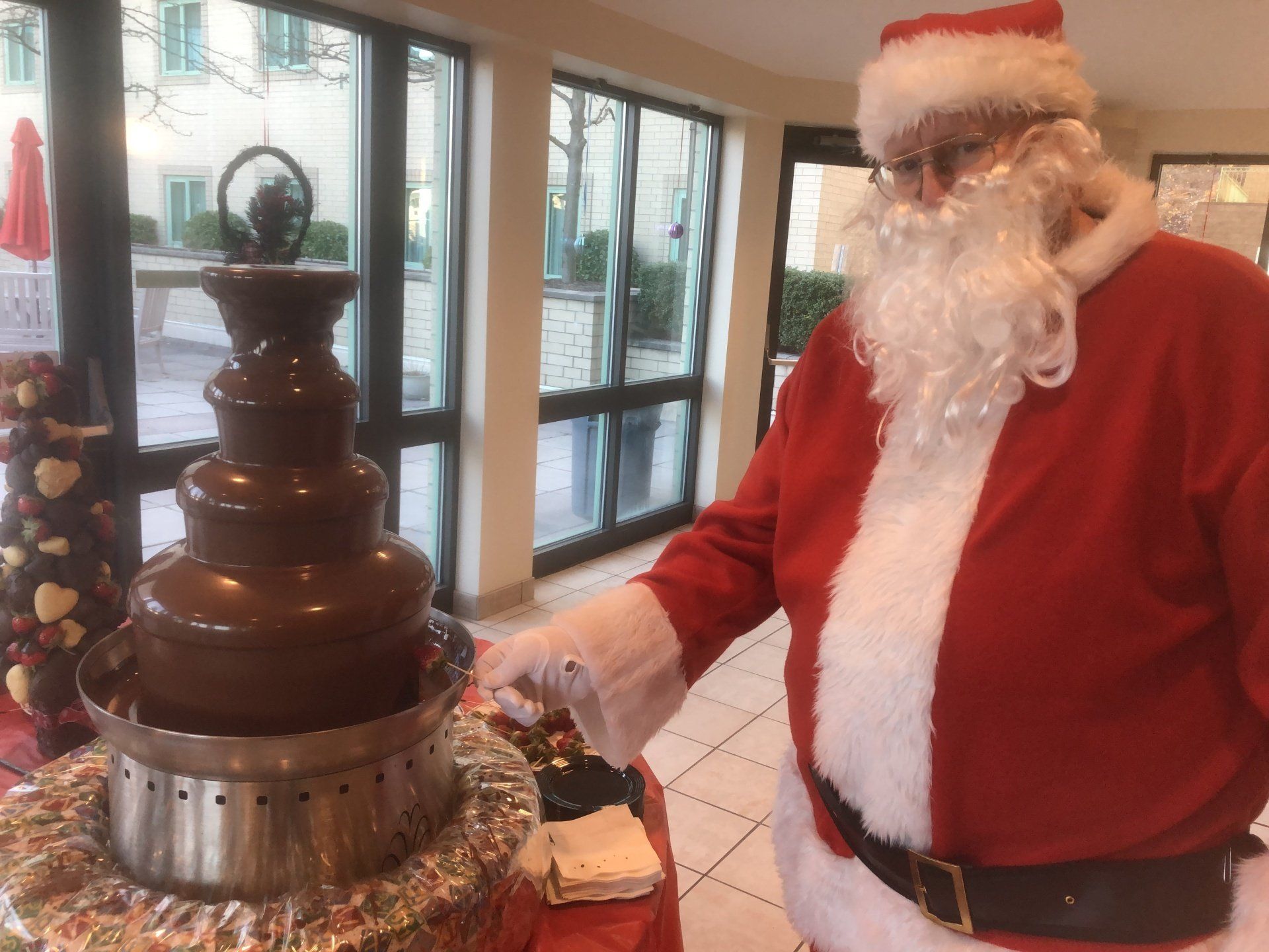 Santa claus is standing in front of a chocolate fountain.