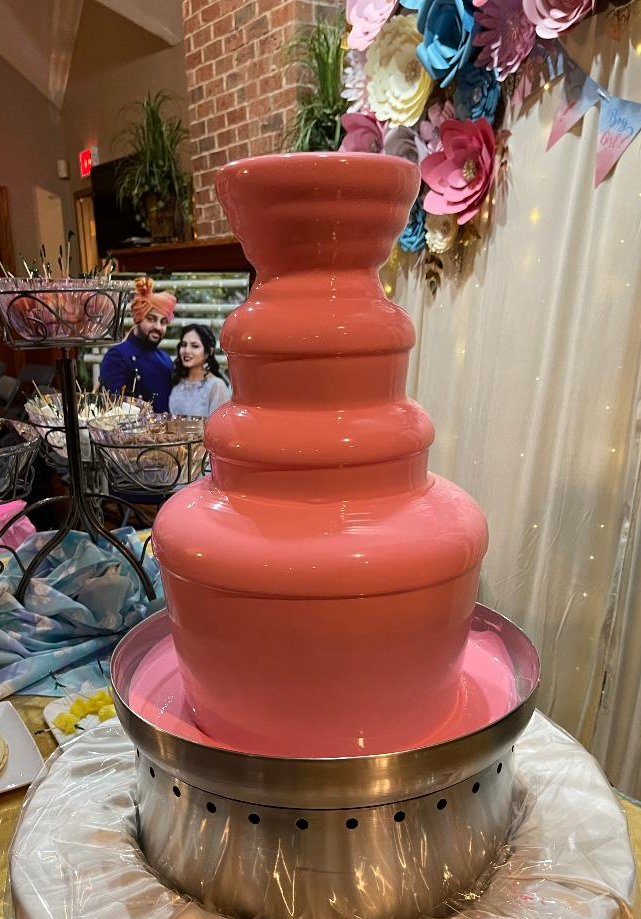 A pink chocolate fountain is sitting on top of a table.