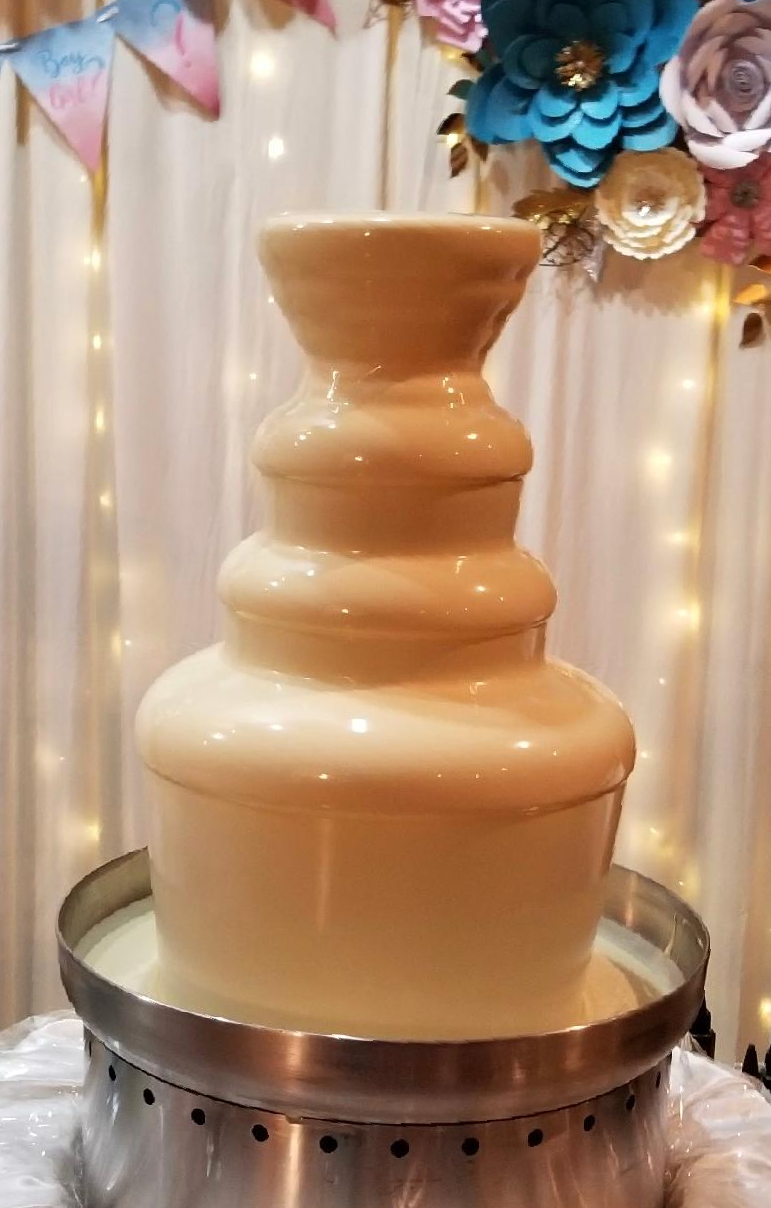 A white chocolate fountain is sitting on a table.