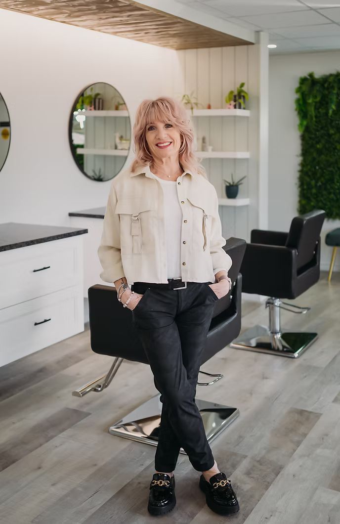 A woman is standing in a salon next to a chair.