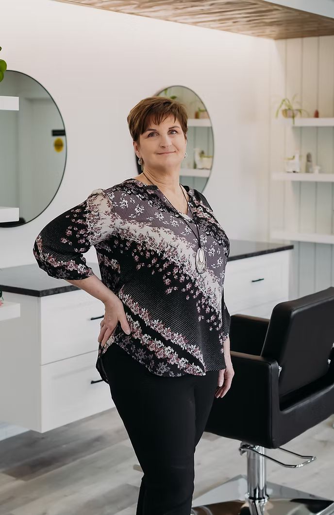 A woman is standing in front of a hair salon chair.