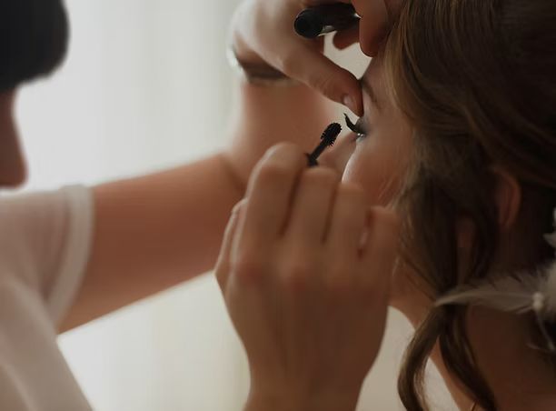 A woman is getting her eye makeup done by a makeup artist