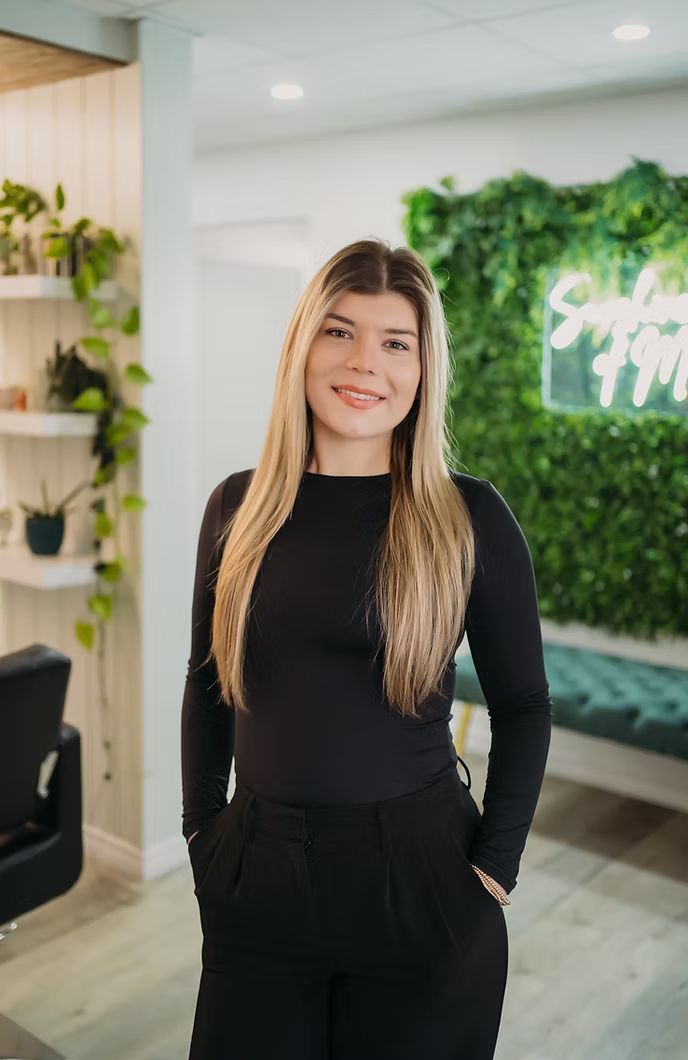 A woman is standing in a room with her hands in her pockets.