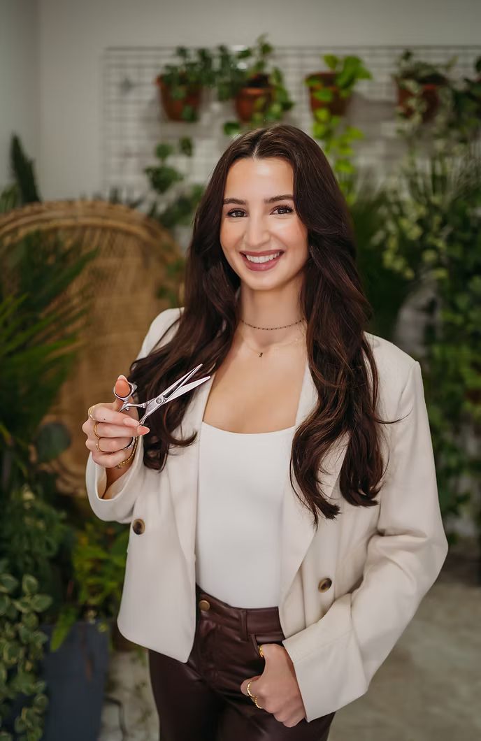 A woman is holding a pair of scissors in her hand and smiling.