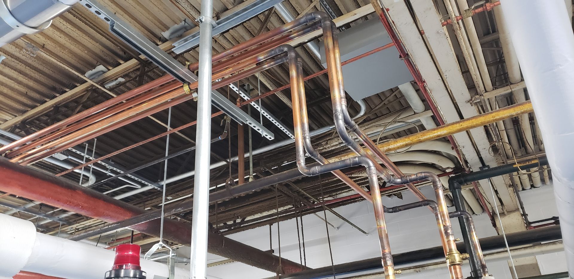 A bunch of pipes are hanging from the ceiling of a building.