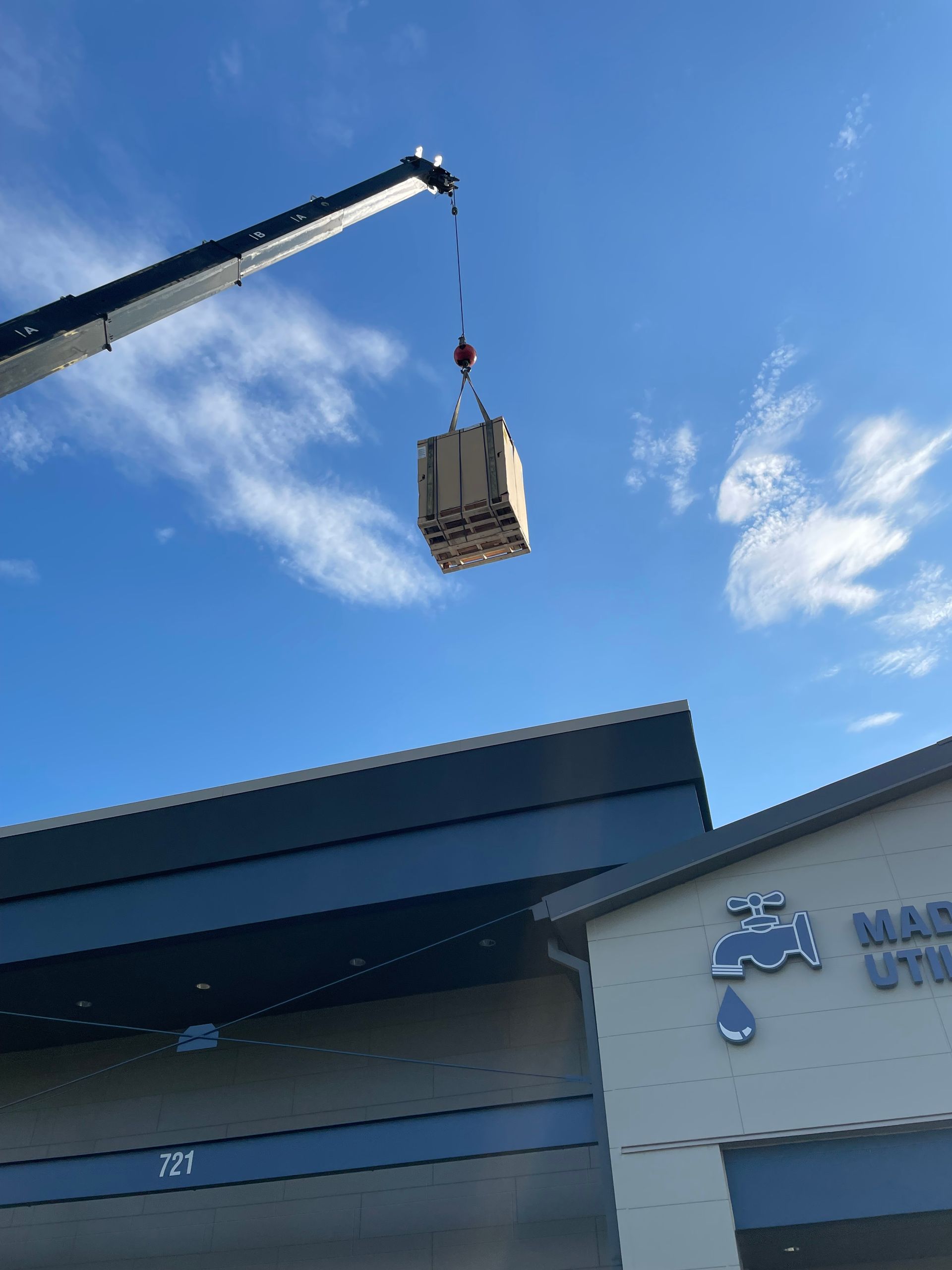 A crane is lifting a box into the air over a building
