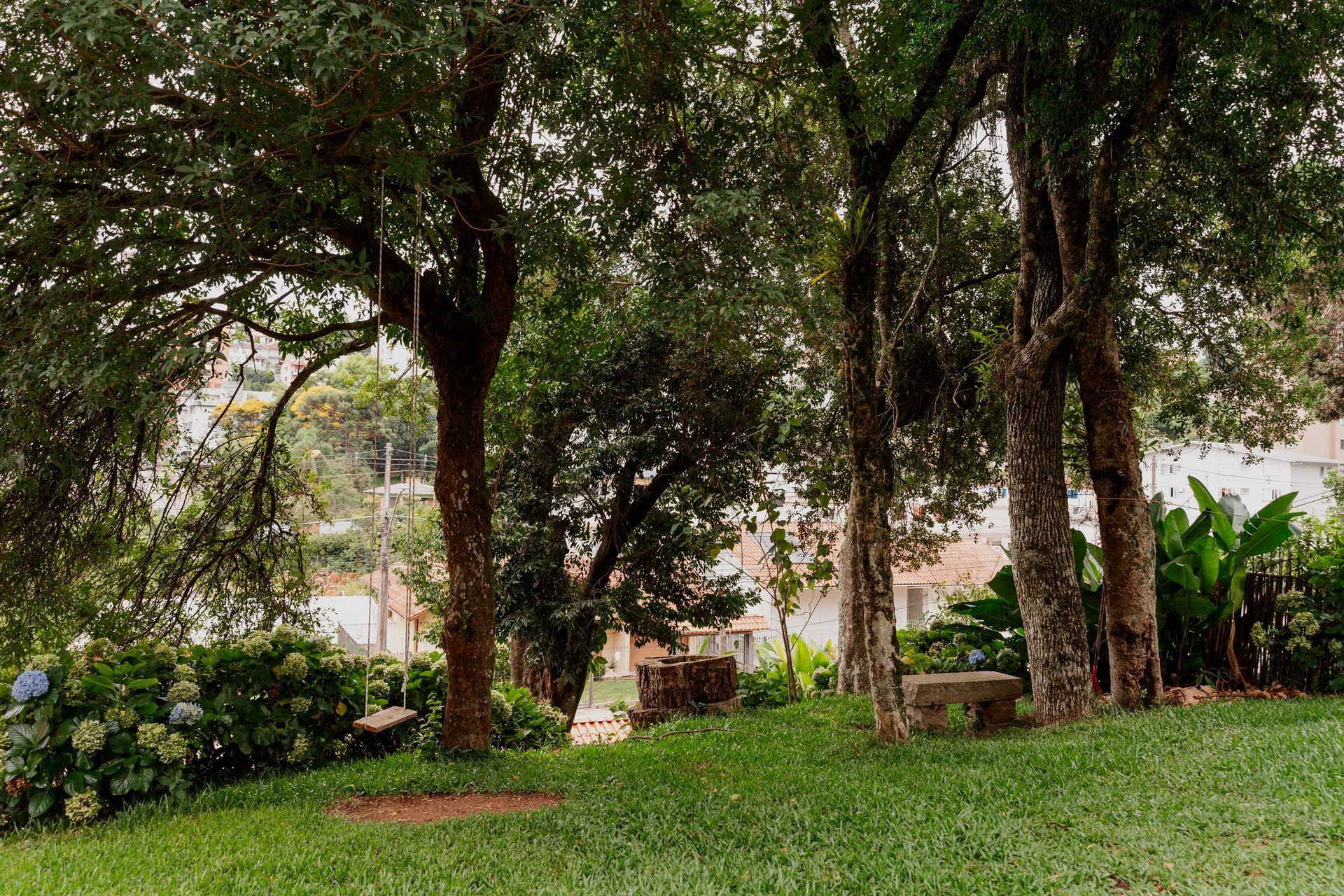 Um parque verdejante com árvores e bancos no meio.- Pousada Santo Antônio