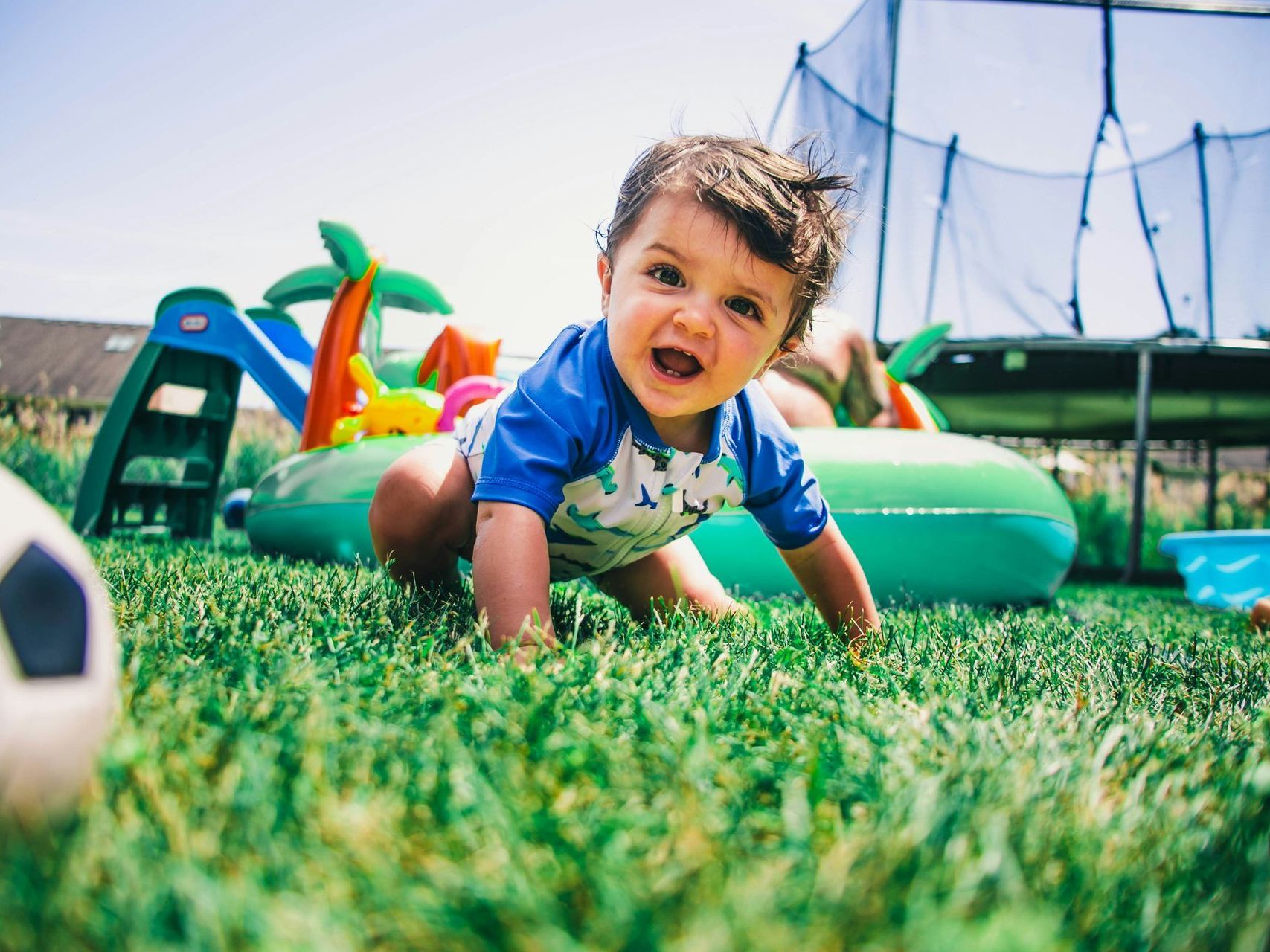 a young boy is running through a field with trees in the background .