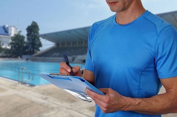 A man in a blue shirt is holding a clipboard and writing on it.