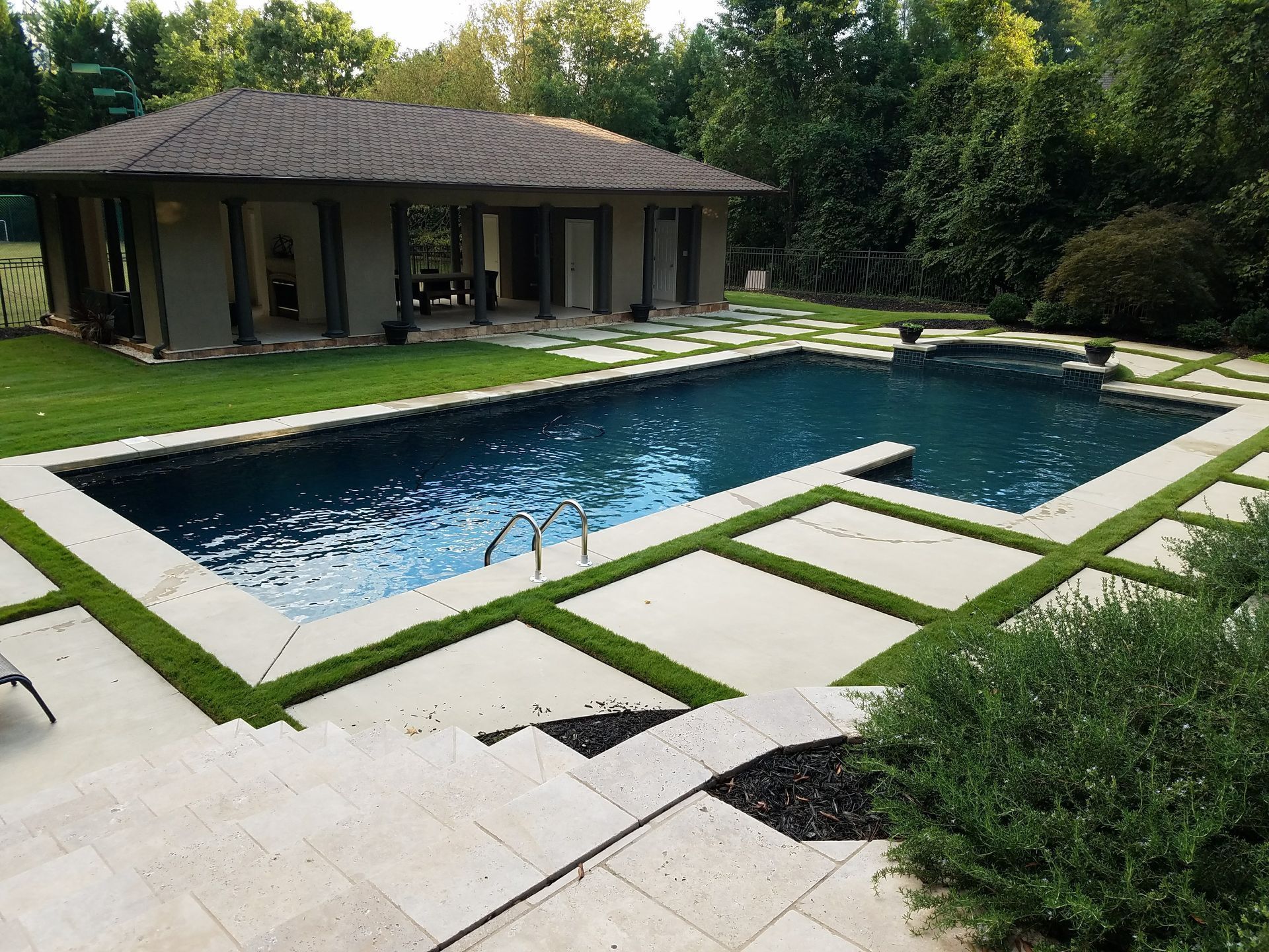 A large swimming pool with a house in the background