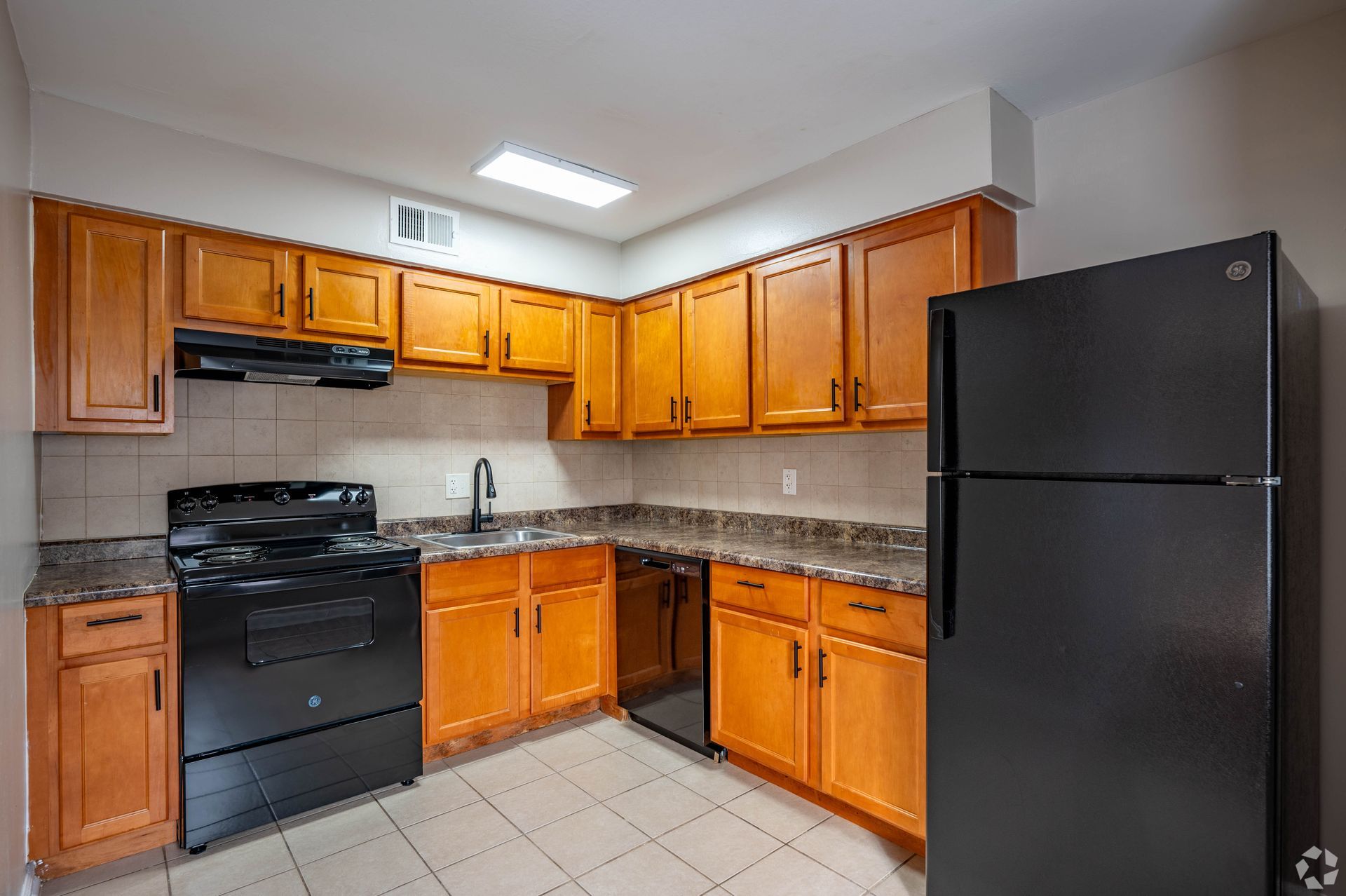 Kitchen with wood cabinets, black appliances, and granite countertops.