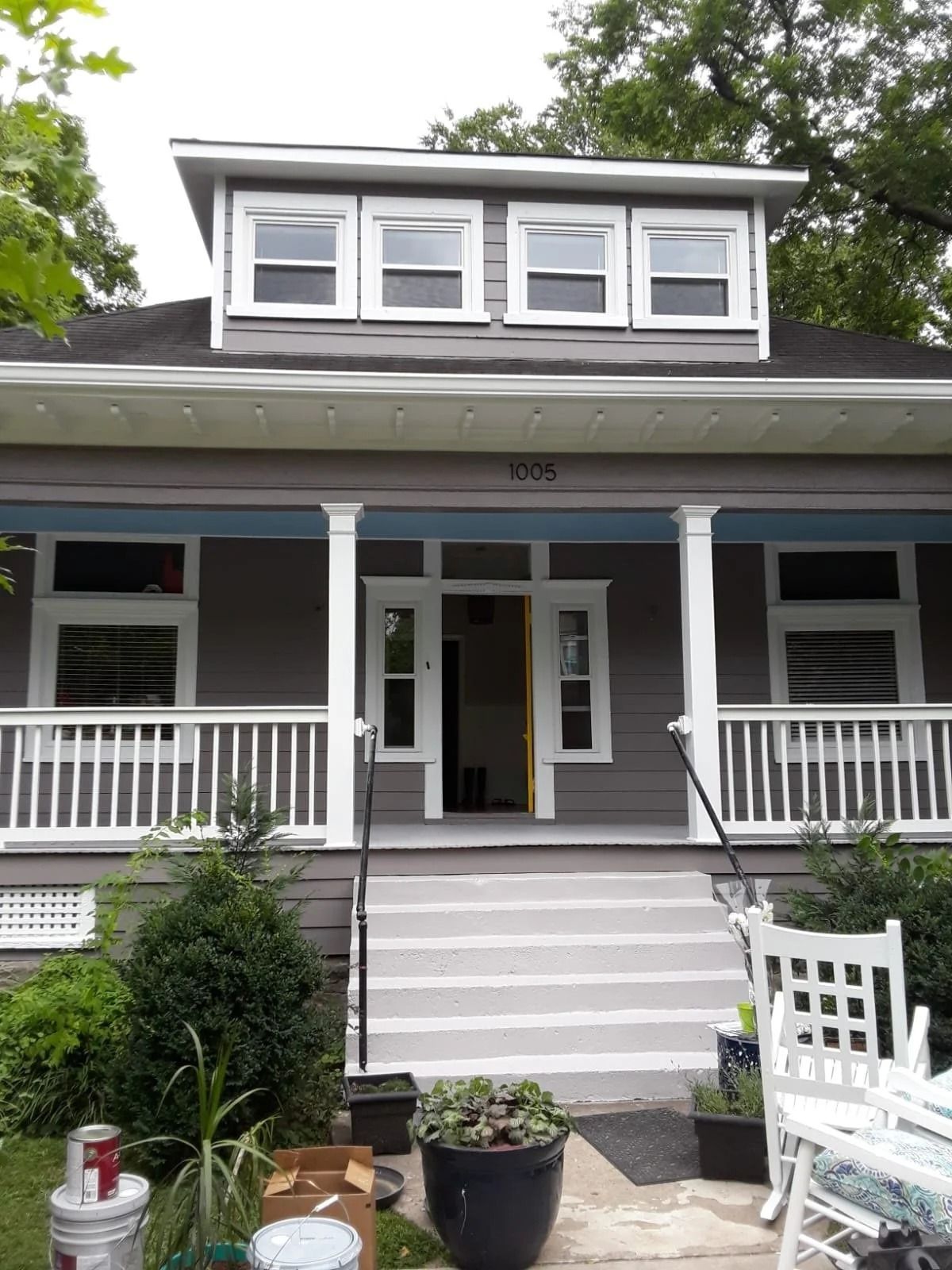 Gray house with porch and steps, featuring a dormer with three windows.