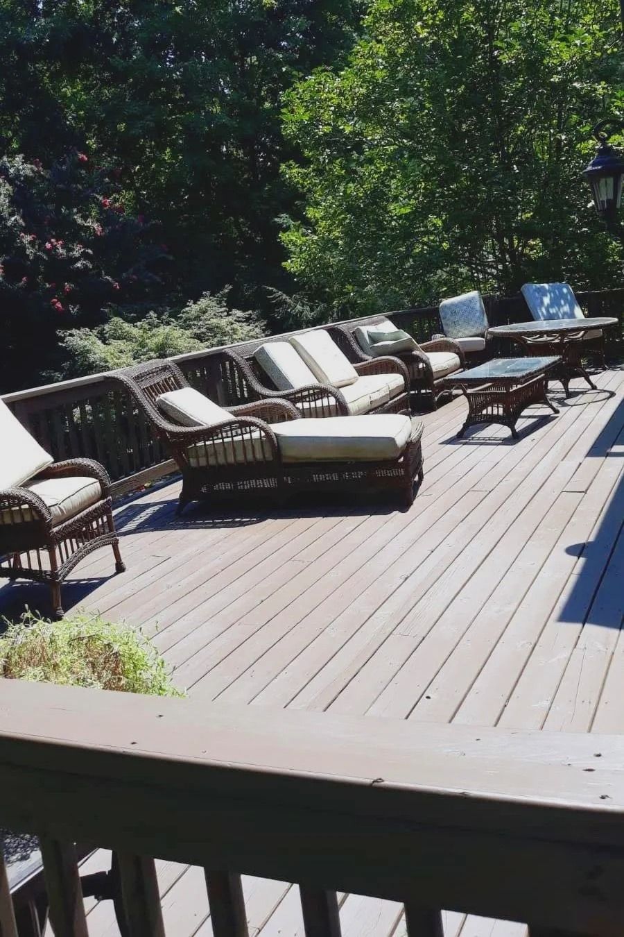 Wooden deck with wicker patio furniture; sunny outdoor setting.