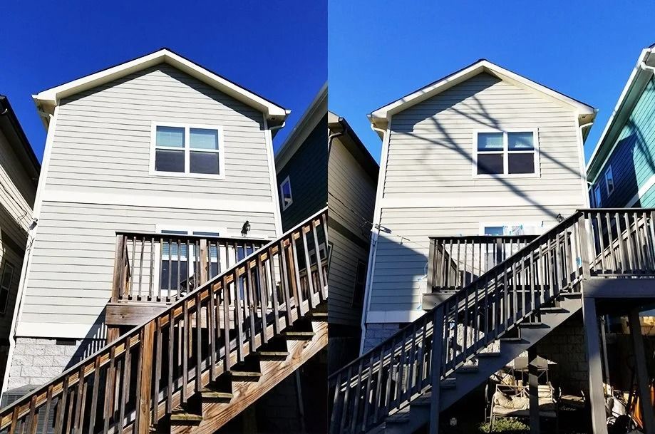 Two-story light gray house with wooden stairs and a blue sky.