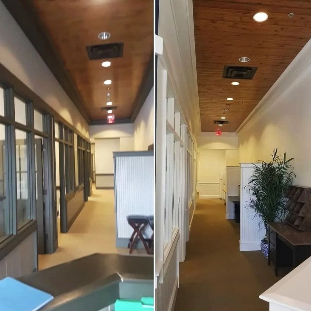 Hallway with wood ceiling, recessed lights, and doors on either side. White walls, dark trim.