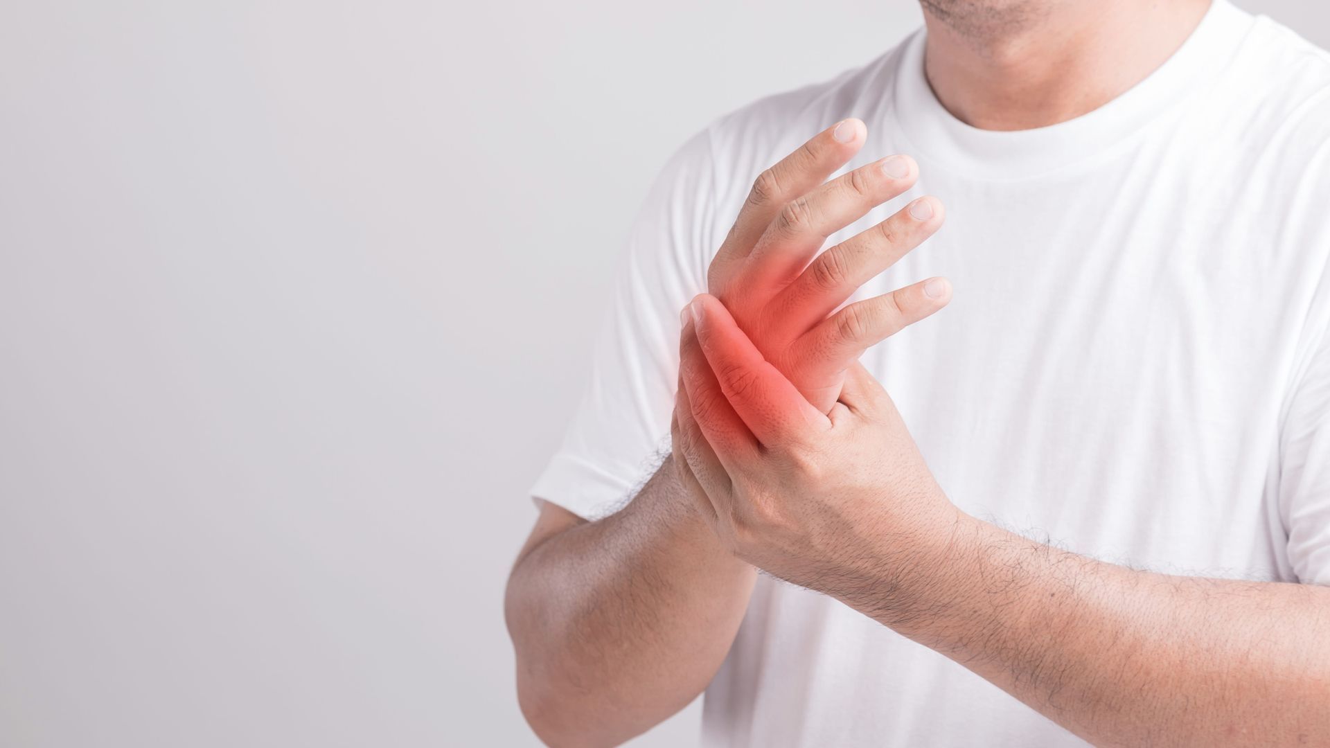 Person holding a painful wrist with red highlighted area on the hand and forearm