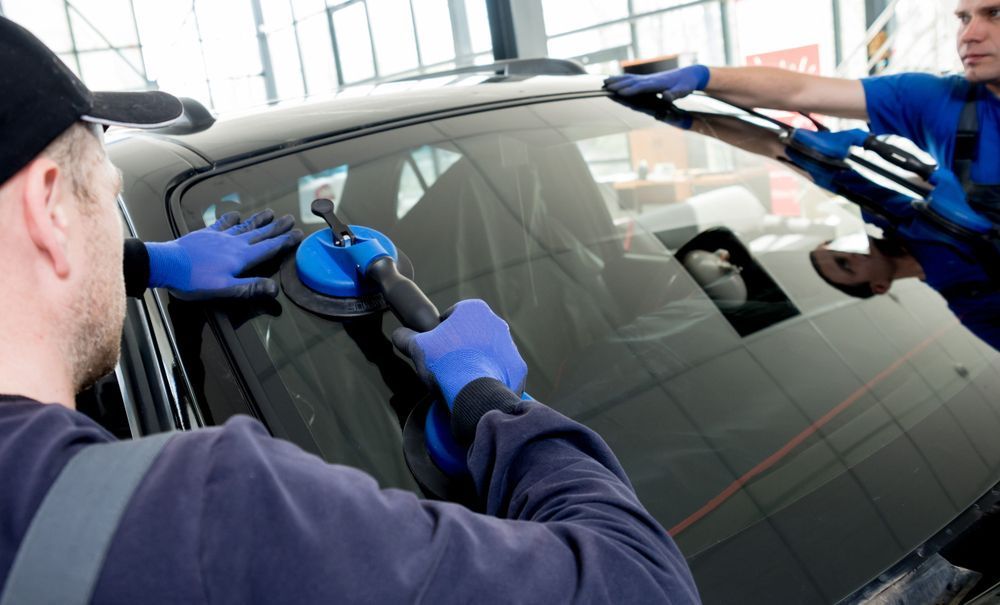 A Man is Installing a Windshield on a Car — O'Brien Carglass & Tinting in Mareeba, QLD