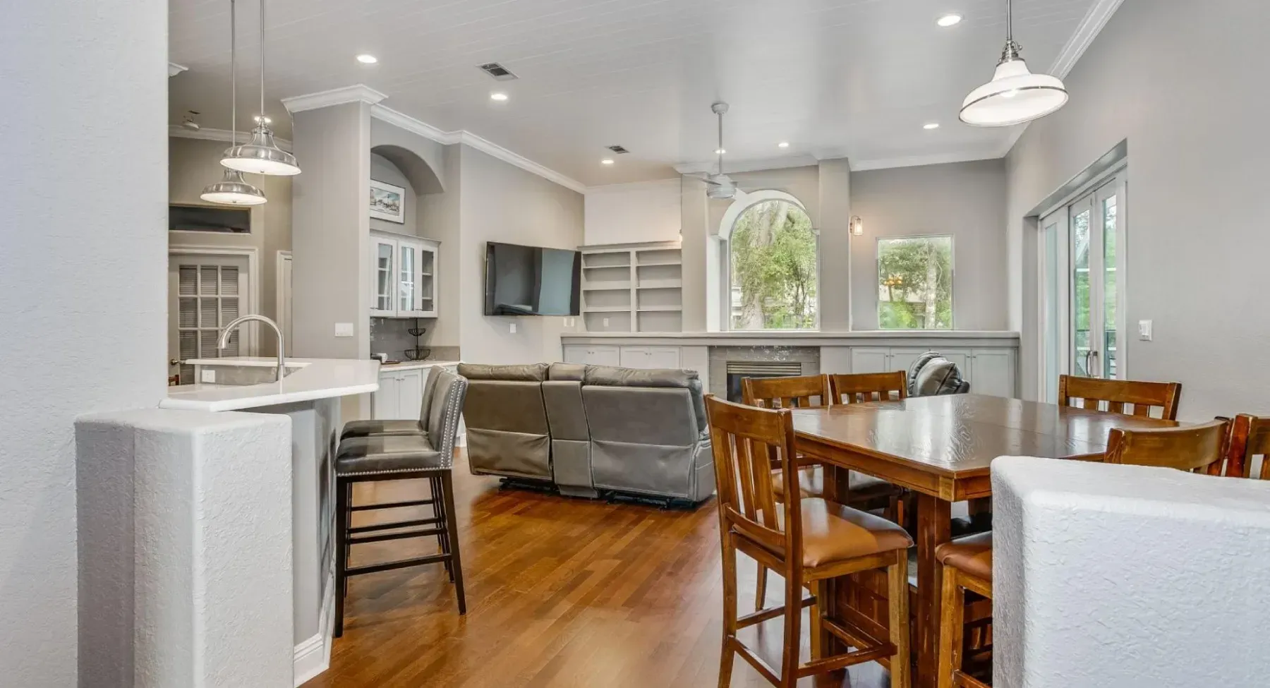 Open-concept living space with dining area, kitchen island, and living room with built-in shelves and sliding glass doors.