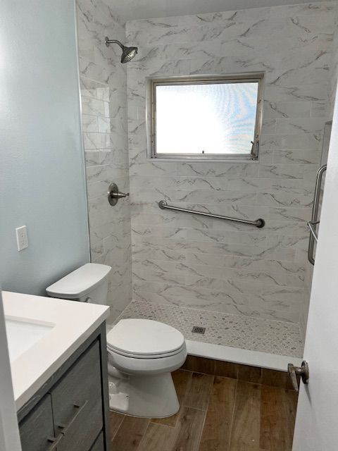 Bathroom with blue and white tile, shower, toilet, and a grab bar.