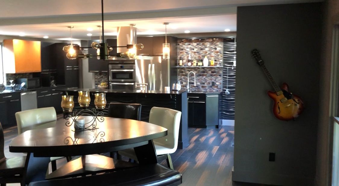Kitchen with dark cabinets, a dining table, and a guitar on the wall.