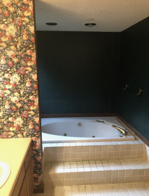 Bathroom with a built-in jacuzzi tub, steps, floral wallpaper, dark green walls, and beige tiles.