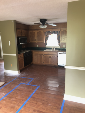 Kitchen with wood cabinets, black appliances, and green walls.
