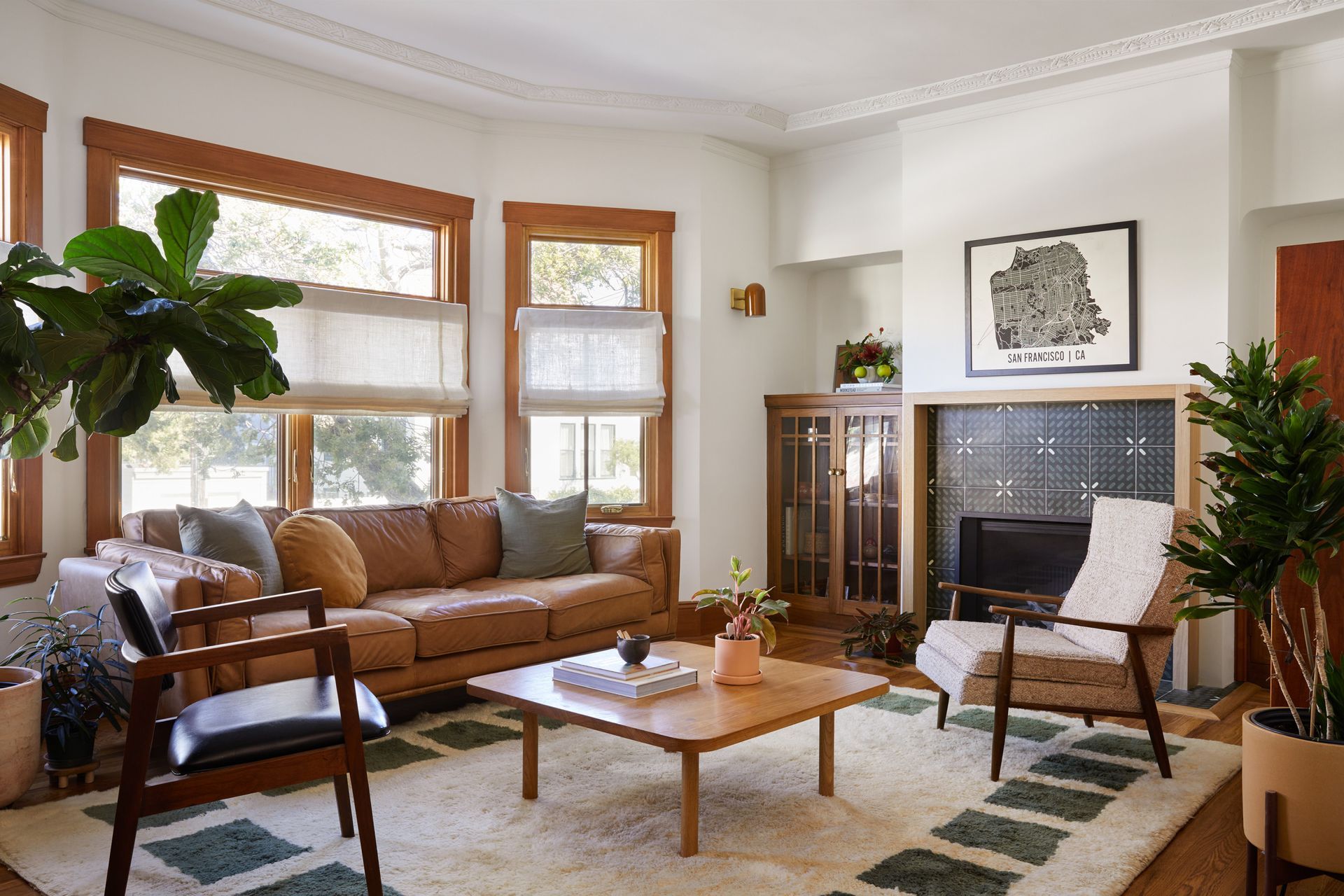 Cozy living room with brown leather sofa, wood chairs, fireplace, and large windows.
