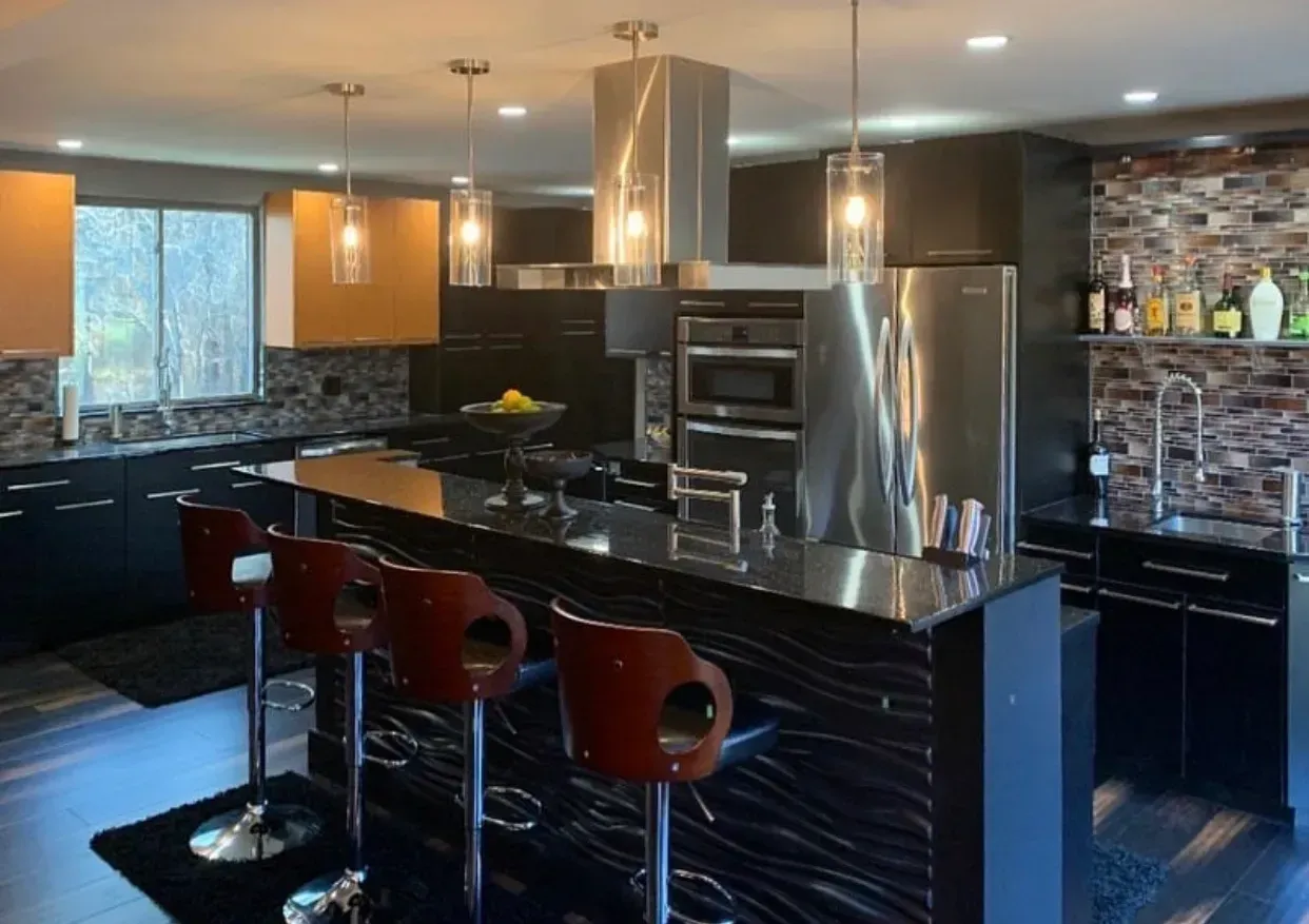 Modern kitchen with black cabinetry, a central island with bar stools, and stainless steel appliances.