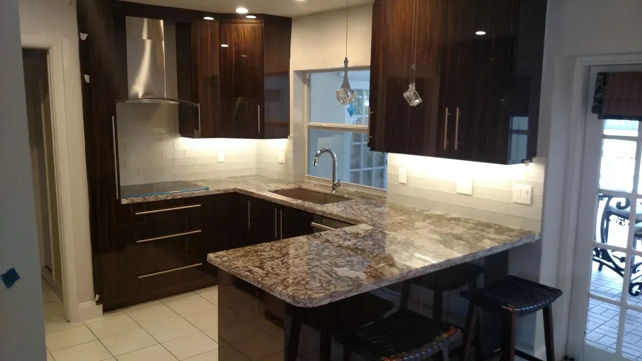 Modern kitchen with dark brown cabinets, granite countertops, and a breakfast bar with stools.