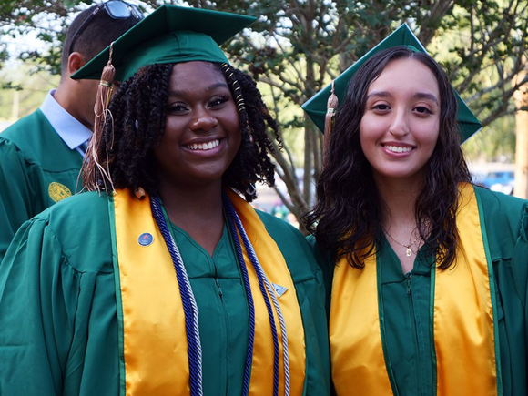 Two female graduates are posing for a picture together