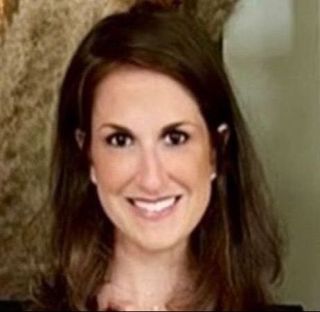 A woman with long brown hair is smiling for the camera.