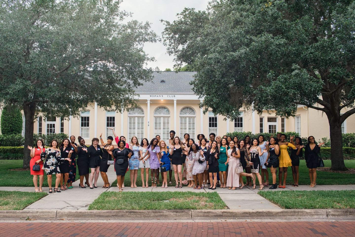 A group of women are posing for a picture in front of a house.