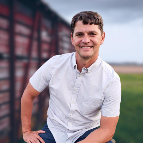 A man in a white shirt is sitting in front of a train car.