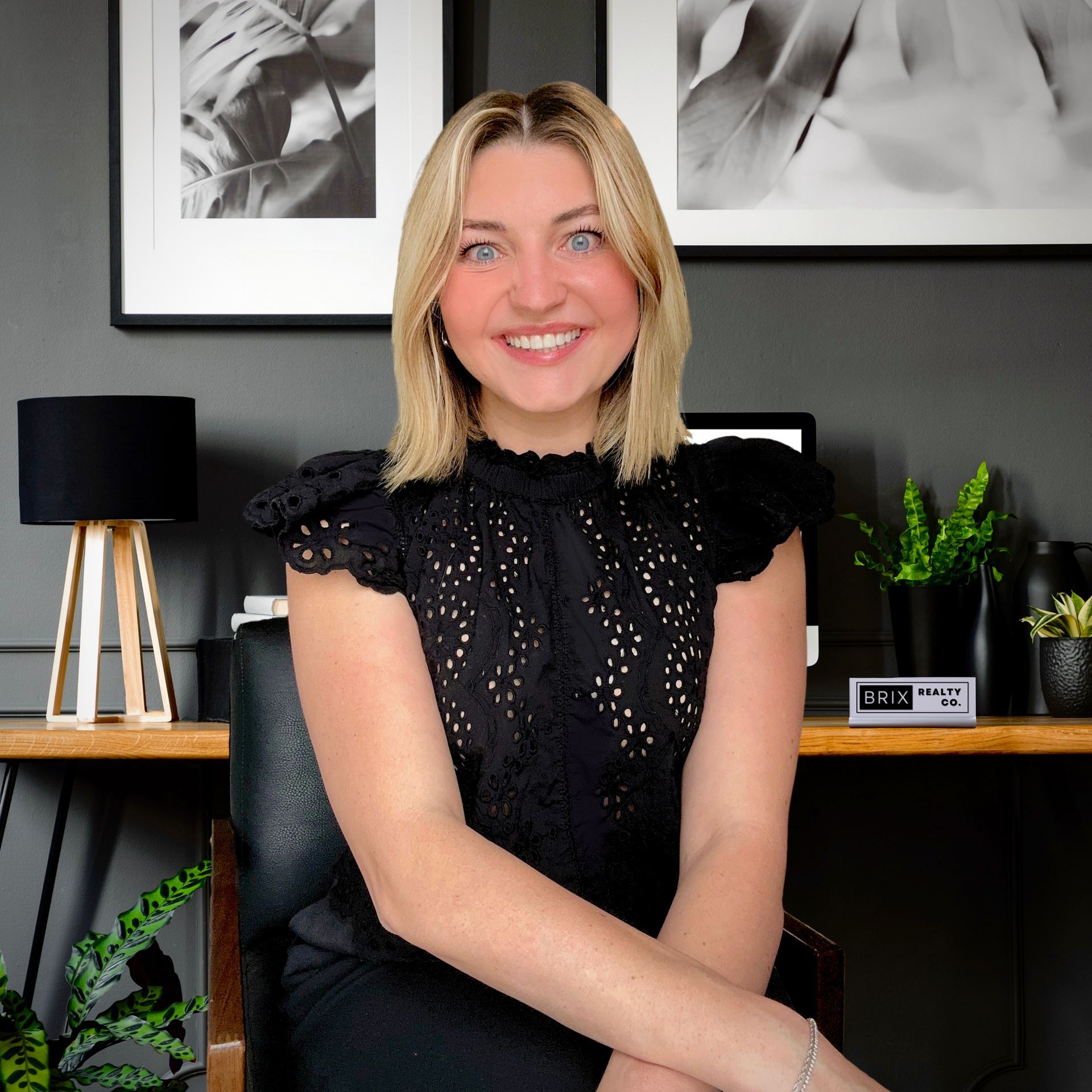 A woman in a black dress is sitting in front of a desk