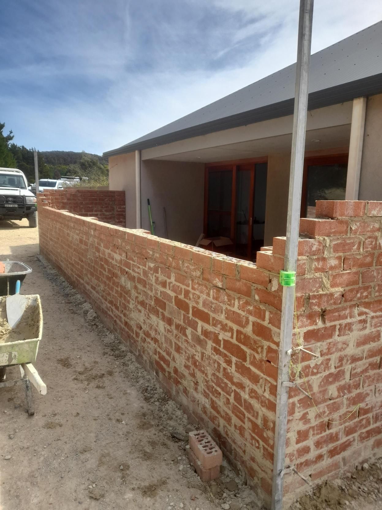 Gray concrete fence with protruding pillars in a residential area, gravel base.