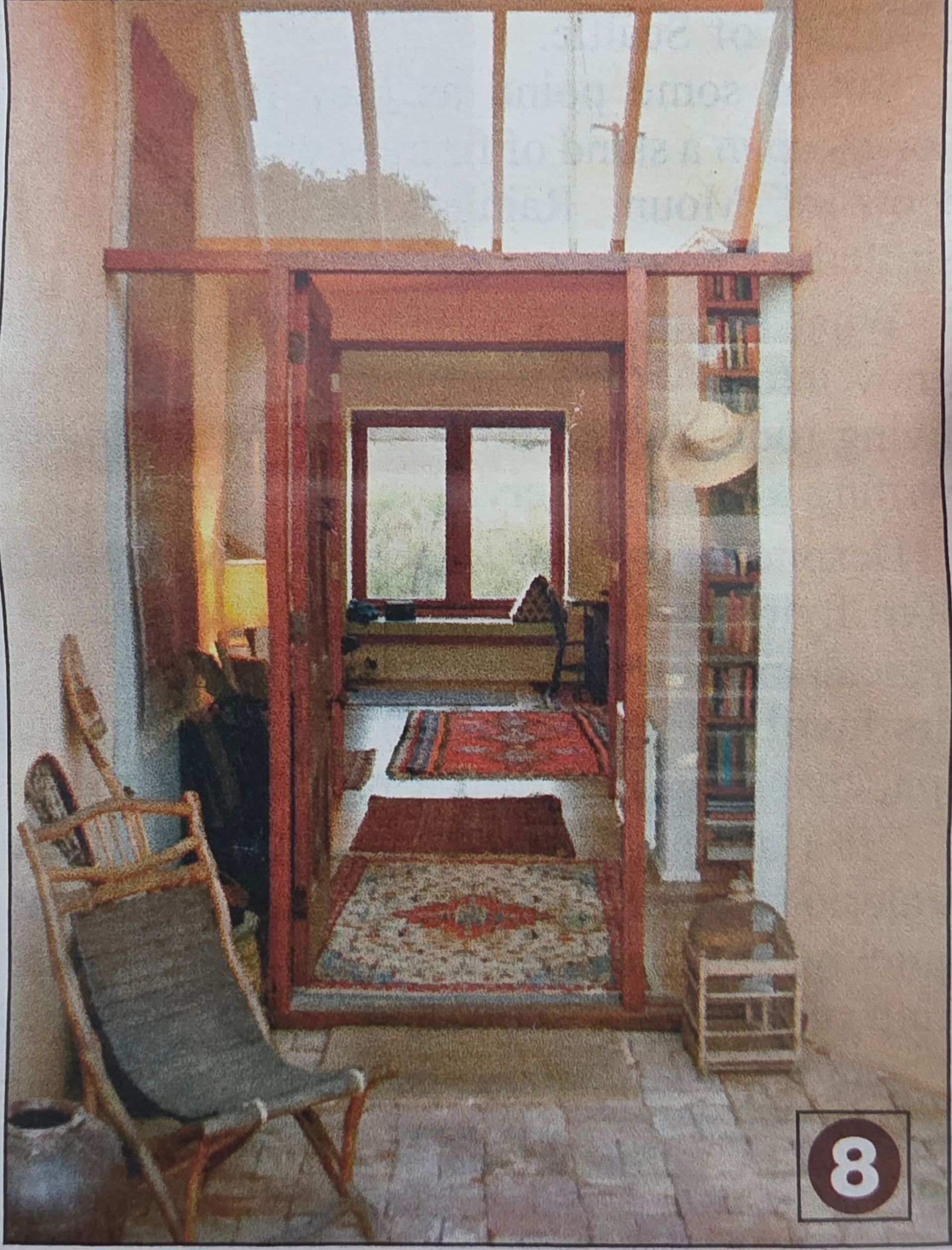 Open doorway leads to interior with rugs, a bookcase, and a seated area; outdoor seating in the foreground.