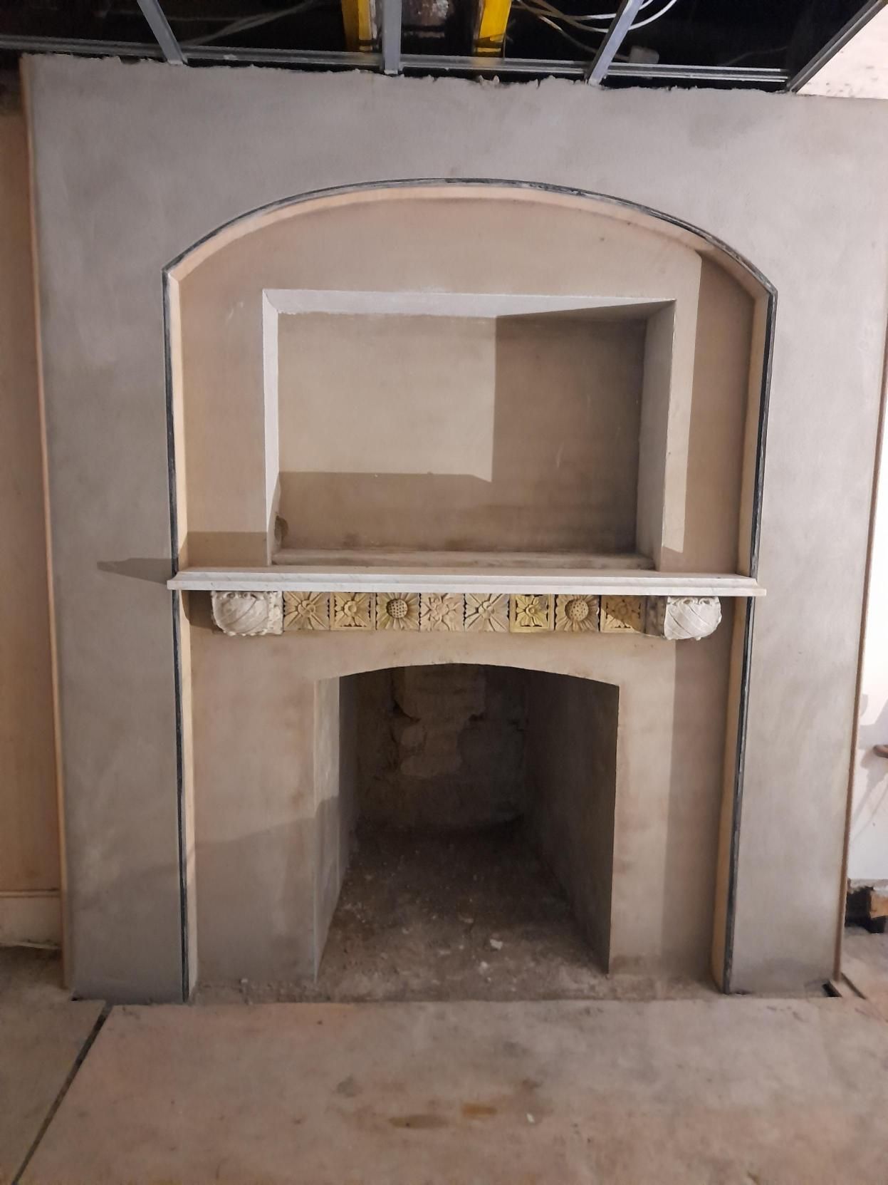 Concrete pillars frame a weathered gray wooden gate, leading to a path covered in fallen autumn leaves.