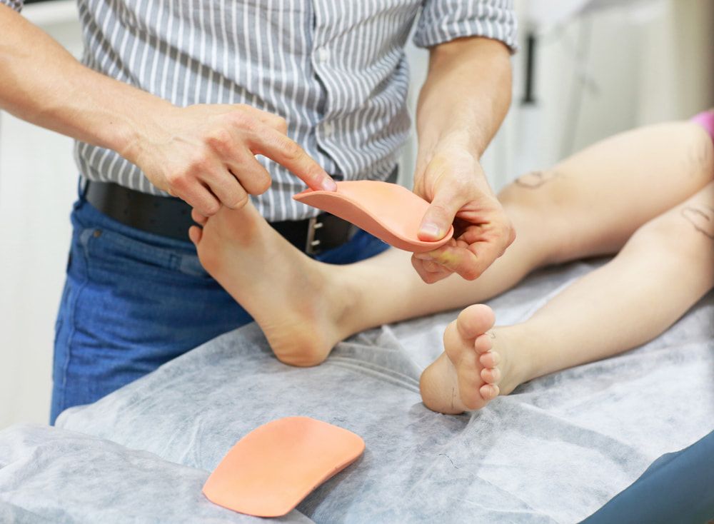 A Person Is Lying On A Bed While A Doctor Examines Their Foot — Lake Macquarie Podiatry in Belmont, NSW