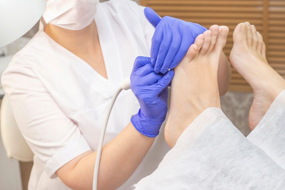 A Woman Is Giving A Foot Treatment To A Patient — Lake Macquarie Podiatry in Rathmines, NSW