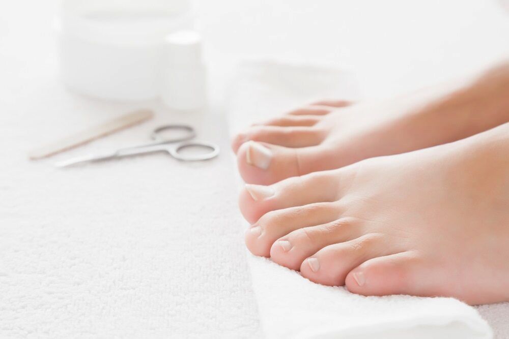 A Woman 's Feet Are Sitting On A White Towel Next To A Pair Of Scissors — Lake Macquarie Podiatry in Belmont, NSW
