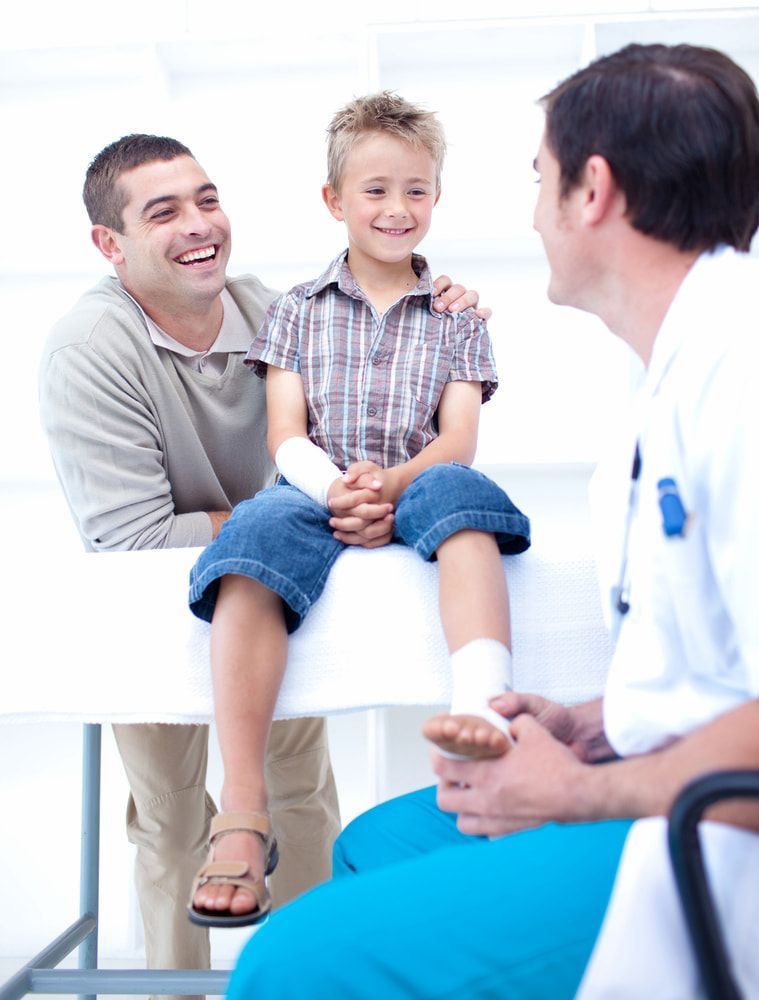 A Doctor Is Talking To A Little Boy With A Cast On His Foot — Lake Macquarie Podiatry in Belmont, NSW