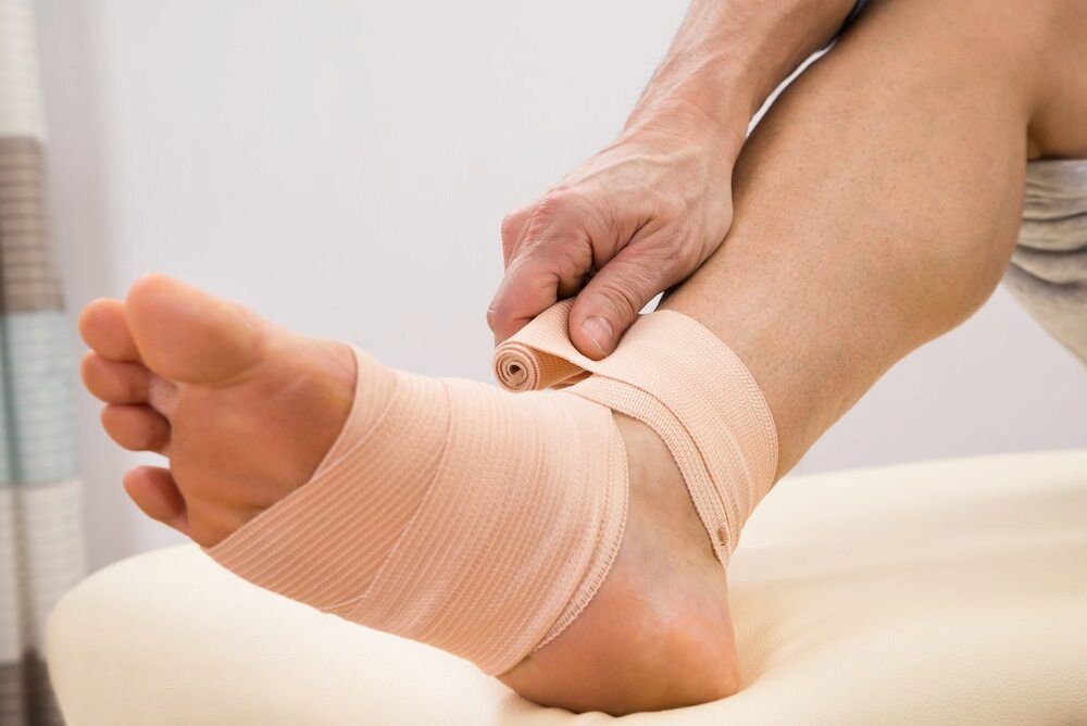 A Person Is Wrapping Their Ankle With A Bandage — Lake Macquarie Podiatry in Belmont, NSW