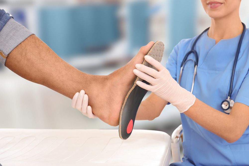 A Nurse Is Examining A Patient's Foot With A Shoe Insole — Lake Macquarie Podiatry in Belmont, NSW