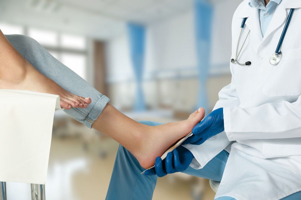 A Doctor Is Examining A Patient's Foot In A Hospital — Lake Macquarie Podiatry in Belmont, NSW