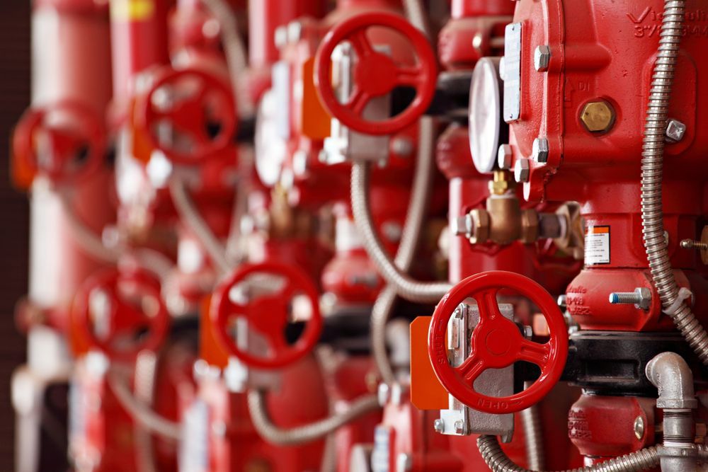 A Row of Red Valves and Pipes in a Factory — Gastech Plumbing Services in Rural View, QLD