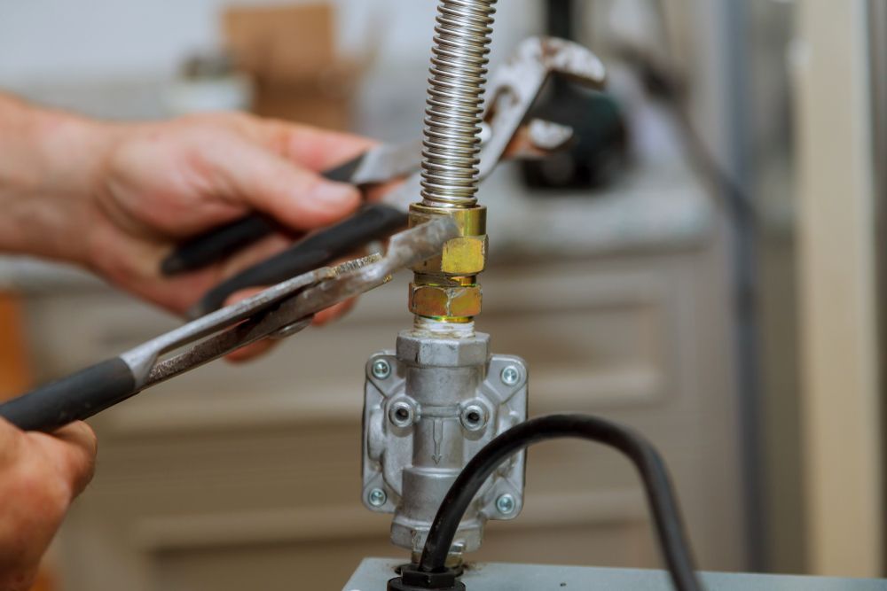A Person is Fixing a Gas Hose With a Wrench and Pliers — Gastech Plumbing Services in Marian, QLD